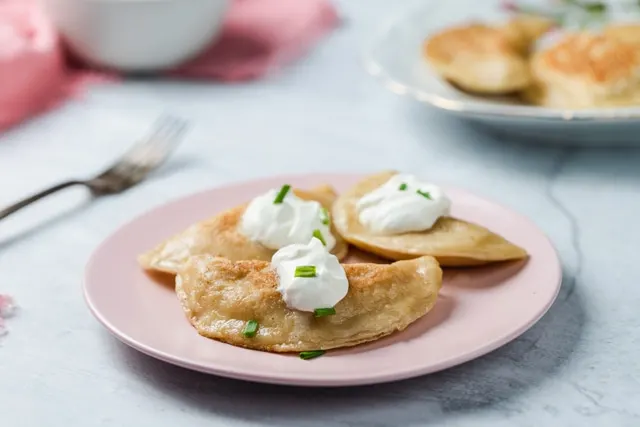 A plate of Polish pierogi topped with sour cream