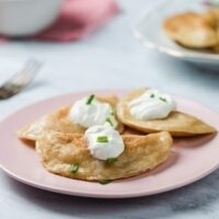 A plate of Polish pierogi topped with sour cream