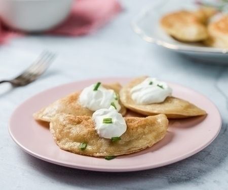 A plate of Polish pierogi topped with sour cream