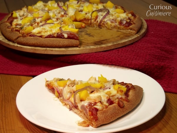 This Mango BBQ Chicken Pizza combines a sweet mango barbecue sauce with chicken and the unlikely sweet pizza topping of fresh mangoes for one delicious pizza that reminds us of a summer barbecue.   | Curious Cuisiniere