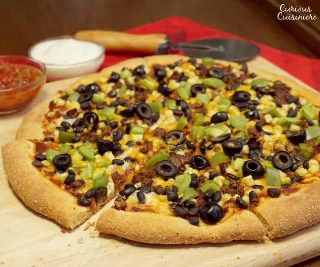 This Cornmeal Pizza Crust recipe is quick and easy to make. Load up your Mexican Pizza with your favorite Mexican inspired toppings for an easy weeknight meal! | www.CuriousCuisiniere.com