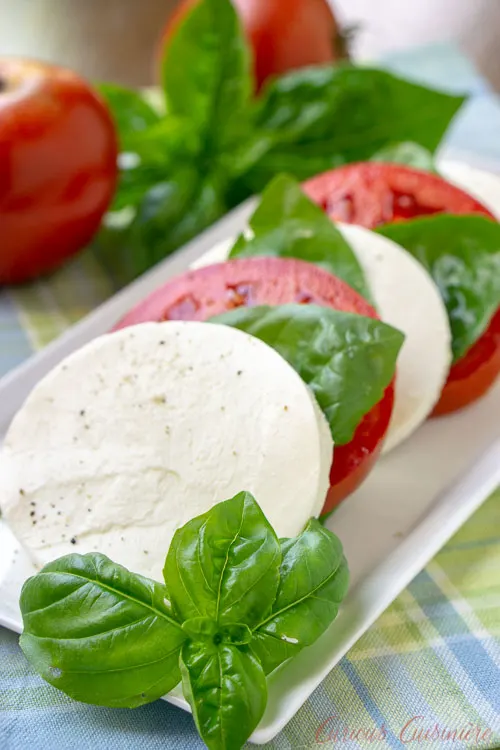 A summer favorite Insalata Caprese (or Caprese Salad), with rounds of fresh mozzarella, ripe tomatoes, and garden basil. | www.CuriousCuisiniere.com 