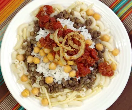 Often called the national dish of Egypt, Kushari is a hearty combination of flavors and textures all topped off with spicy tomato sauce and fried onions. | www.CuriousCuisiniere.com