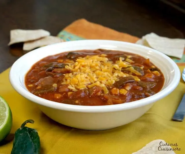 This slow cooker Vegetarian Enchilada Soup is packed full of flavorful peppers and hearty beans for a quick weeknight meal. | www.CuriousCuisiniere.com