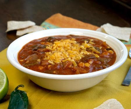 This slow cooker Vegetarian Enchilada Soup is packed full of flavorful peppers and hearty beans for a quick weeknight meal. | www.CuriousCuisiniere.com