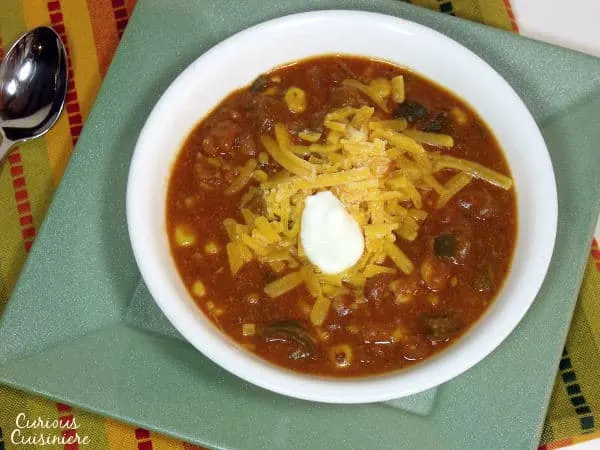 This slow cooker Cheesy Vegetarian Enchilada Soup is packed full of flavorful peppers and hearty beans for a quick weeknight meal. | www.curiouscuisiniere.com
