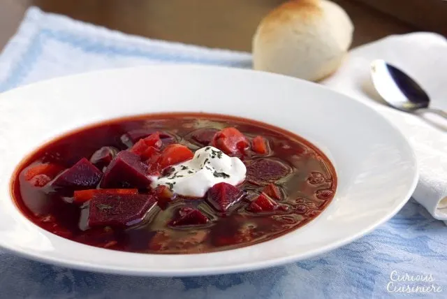 Our Polish Borscht recipe (Barszcz) creates a beet soup that is chock full of veggies and boasts a bright, sweet and sour flavor making it a perfect first course or warming meal. | www.CuriousCuisiniere.com