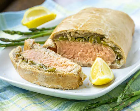 Lemon rosemary salmon en croute with asparagus on a white plate.