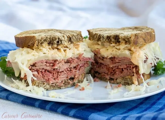 The classic grilled Reuben Sandwich is the perfect combination of crispy toast, flavorful corned beef, tangy sauerkraut, and creamy Russian dressing. | www.CuriousCuisiniere.com