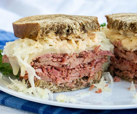 The classic grilled Reuben Sandwich is the perfect combination of crispy toast, flavorful corned beef, tangy sauerkraut, and creamy Russian dressing. | www.CuriousCuisiniere.com