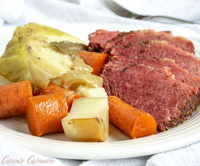 A plate of corned beef brisket with cabbage, potatoes, and carrots.