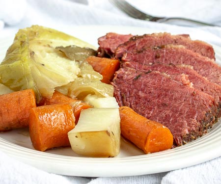 A plate of corned beef brisket with cabbage, potatoes, and carrots.