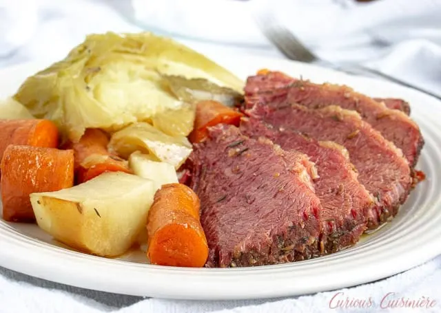 A plate of corned beef brisket with cabbage, potatoes, and carrots.