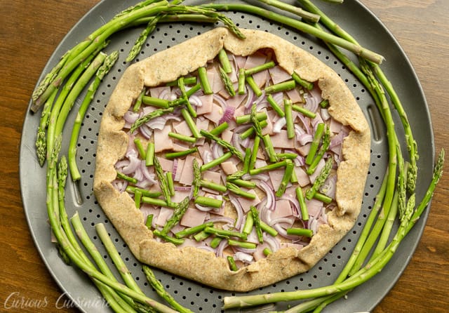 This Ham and Asparagus Tart is light and perfect for spring with strips of leftover ham and thin asparagus spears, roasted perfectly in a lemon herb crust. | www.CuriousCuisiniere.com