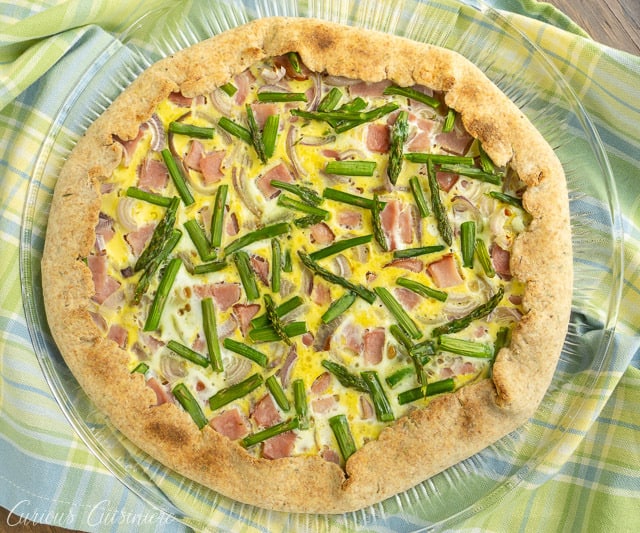 This Ham and Asparagus Tart is light and perfect for spring with strips of leftover ham and thin asparagus spears, roasted perfectly in a lemon herb crust. | www.CuriousCuisiniere.com