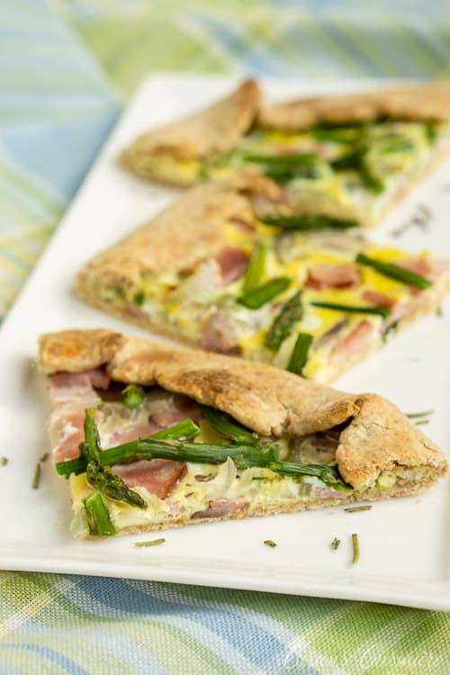This Lemon Asparagus Tart is light and perfect for spring with strips of leftover ham, red onion, and thin asparagus spears, roasted perfectly in a lemon herb crust. | www.CuriousCuisiniere.com