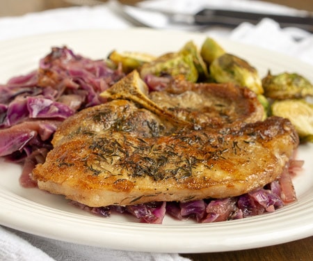 Bring a taste of fall to your dinner table with this German-inspired skillet recipe of apple cider pork chops with red cabbage. Everything is braised to tender, flavorful perfection! | www.CuriousCuisiniere.com