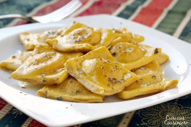 Pumpkin infused homemade pasta makes the perfect vessel for a creamy tarragon cheese filling in this fall Pumpkin Ravioli Recipe.  | www.CuriousCuisiniere.com