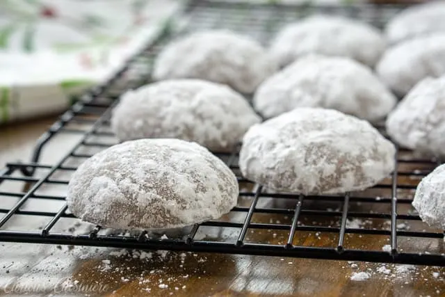 Powdered sugared German Pfeffernusse Spice Cookies on a baking rack horizontal