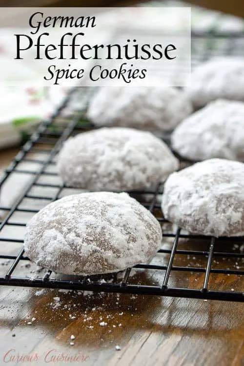 Powdered sugared German Pfeffernusse Spice Cookies on a baking rack with text overlay