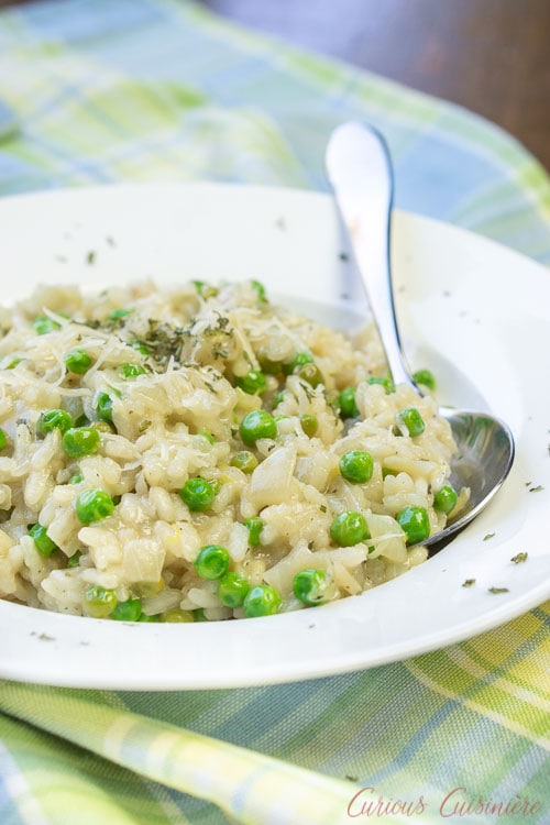 Creamy spring pea risotto in a white bowl with a serving spoon..
