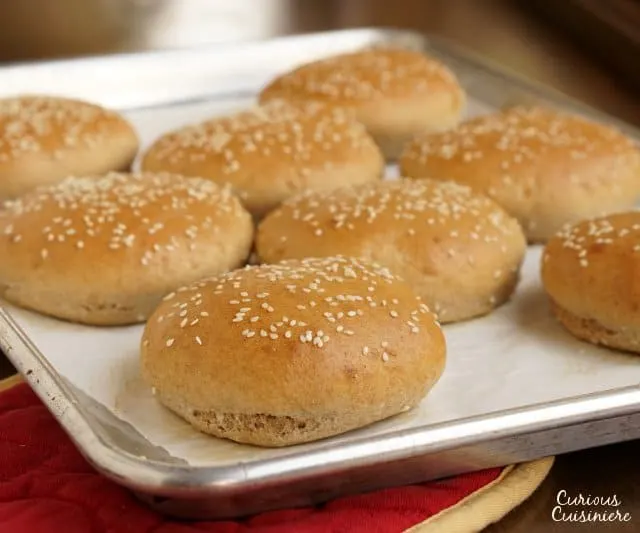 These homemade, wheat hamburger buns go from a pile of ingredients to fluffy, golden buns in less than an hour. | www.CuriousCuisiniere.com