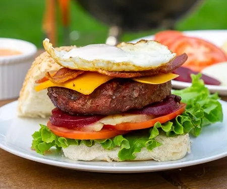 This loaded Australian Hamburger is a mile-high burger with egg, bacon, cheddar cheese, pineapple, pickled beets, sweet onion, lettuce, tomato, and a chili mayo sauce. If you love burger toppings, this Aussie Burger is for you! | www.CuriousCuisiniere.com
