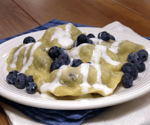 A sweet dessert version of traditional Polish pierogi, filled with blueberries and topped with sweet cream.