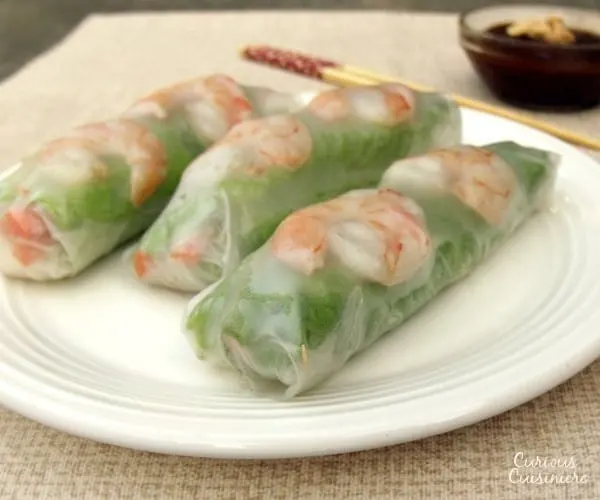 Pork, shrimp, lettuce, fresh herbs, carrots, and rice noodles are wrapped in rice paper, making spring rolls a healthy lunch or snack. Includes detailed instructions on how to wrap and roll a spring roll. | www.curiouscuisiniere.com