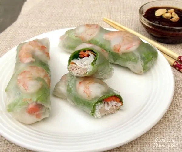 Pork, shrimp, lettuce, fresh herbs, carrots, and rice noodles are wrapped in rice paper, making spring rolls a healthy lunch or snack. Includes detailed instructions on how to wrap and roll a spring roll. | www.curiouscuisiniere.com