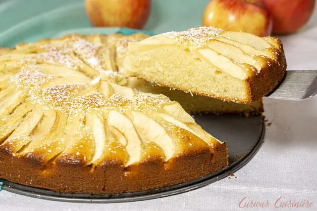 A slice of moist and buttery Apfelkuchen, German Apple Cake, being removed. | www.CuriousCuisiniere.com