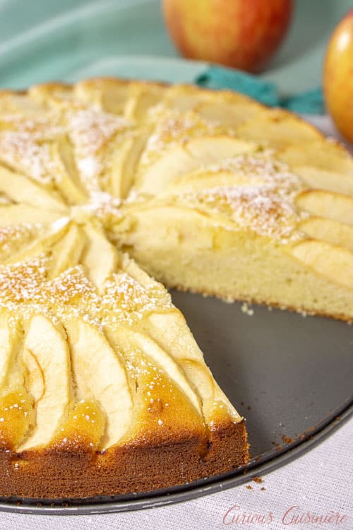 A whole Apfelkuchen, German Apple Cake with a slice removed. | www.CuriousCuisiniere.com