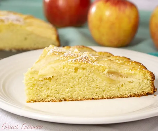 A slice of moist and buttery Apfelkuchen, German Apple Cake, served on a plate. | www.CuriousCuisiniere.com