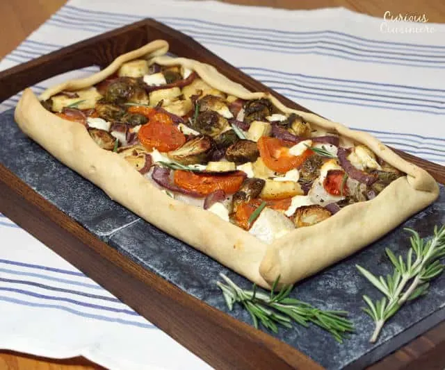 This rustic, free-form Tarte Provencale is filled with flavorful roasted winter vegetables and creamy goat cheese. It is the perfect recipe for a comforting winter appetizer. | www.CuriousCuisiniere.com