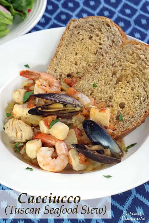 Cacciucco, a hearty Tuscan seafood stew, is served over toasted bread croutons for a fun and comforting meal. | www.CuriousCuisiniere.com