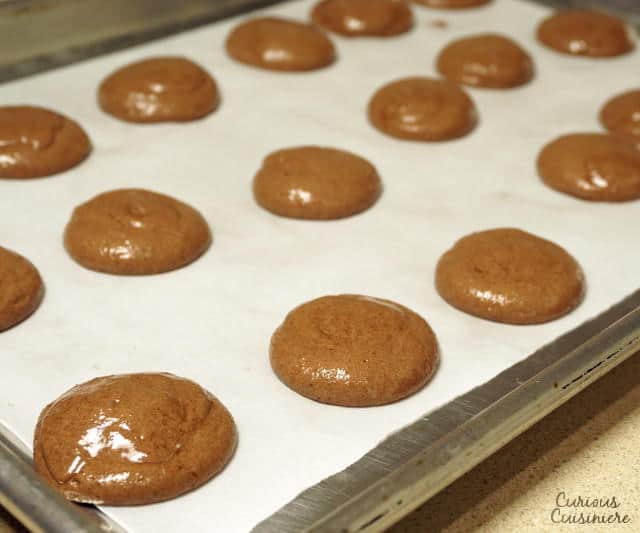 These Chocolate French Macarons combine a soft and fudgy macaron cookie with a raspberry filling for a perfectly delightful combo. | www.CuriousCuisiniere.com