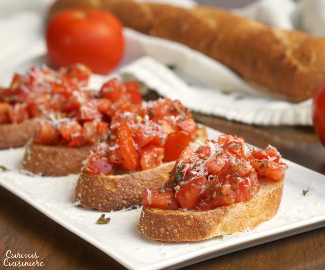 This recipe for a classic Tomato Basil Bruschetta features the perfect, bright and herby tomato topping served over crisp garlic toast. | www.CuriousCuisiniere.com