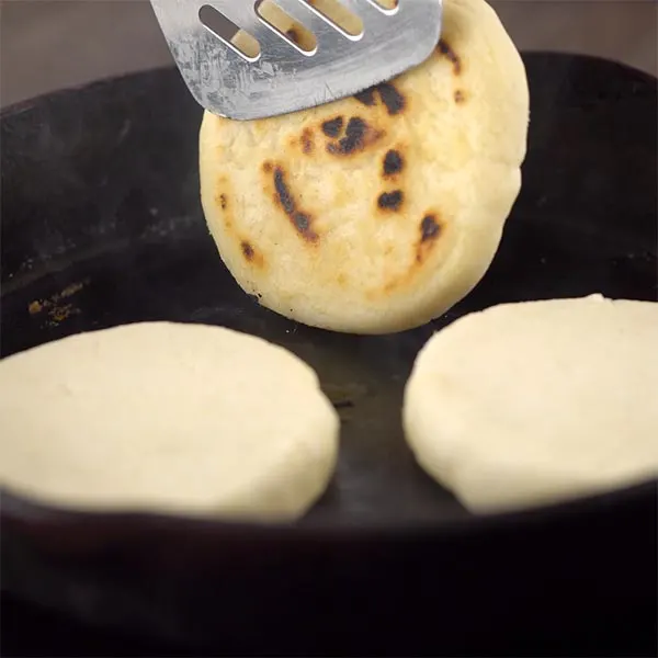 Flipping arepas on the skillet