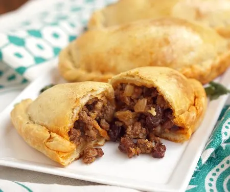 Chilean Empanadas de Pino are flavorful beef empanadas filled with unexpected ingredients like raisins, olives, and hard boiled eggs. These make a great meal on the go and are perfect for a make-ahead meal! | www.CuriousCuisiniere.com