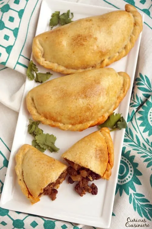 Chilean Empanadas de Pino are flavorful beef empanadas filled with unexpected ingredients like raisins, olives, and hard boiled eggs. These make a great meal on the go and are perfect for a make-ahead meal! | www.CuriousCuisiniere.com