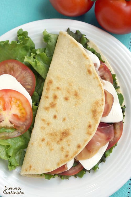 Piadina are thin, Italian flatbreads that are made by street vendors and sold sandwich-style loaded with tasty fillings like fresh mozzarella and flavorful prosciutto.  | www.CuriousCuisiniere.com