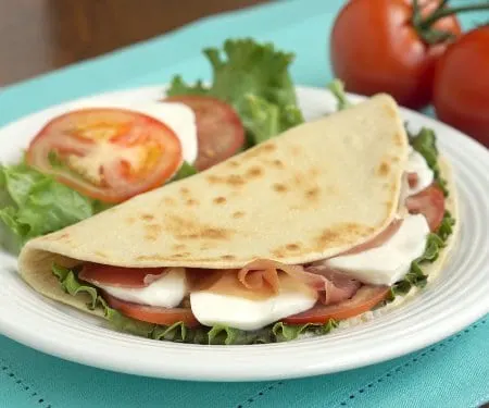 Piadina is a thin, Italian flatbread that is made my street vendors and sold sandwich-style loaded with tasty fillings like fresh mozzarella and flavorful prosciutto. | www.CuriousCuisiniere.com