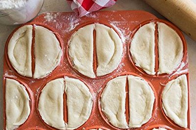 Red pierogi press with just pressed pierogi.