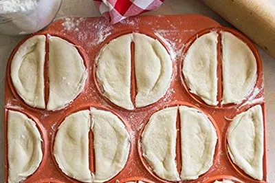 Red pierogi press with just pressed pierogi.