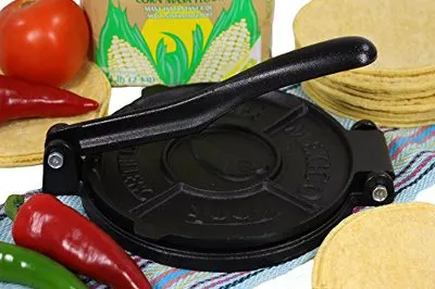 Black iron tortilla press surrounded by ingredients. 