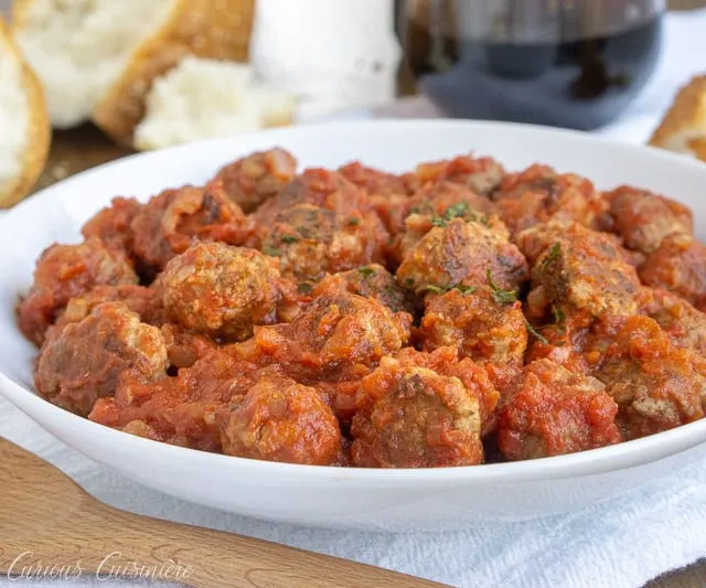 Spanish Meatballs, or Albondigas, are traditionally served at tapas bars in Spain. Whether you serve them for an appetizer, tapas party, or dinner main dish, these small meatballs in a flavorful tomato sauce are perfect for enjoying with a glass of red wine. | www.CuriousCuisiniere.com