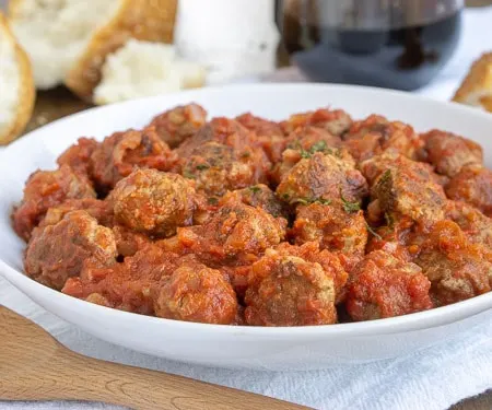 Spanish Meatballs, or Albondigas, are traditionally served at tapas bars in Spain. Whether you serve them for an appetizer, tapas party, or dinner main dish, these small meatballs in a flavorful tomato sauce are perfect for enjoying with a glass of red wine. | www.CuriousCuisiniere.com