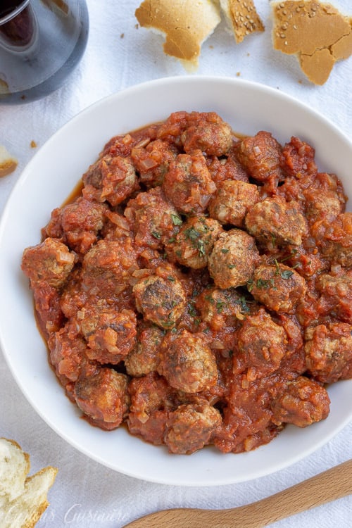 Spanish Meatballs, or Albondigas, are traditionally served at tapas bars in Spain. Whether you serve them for an appetizer, tapas party, or dinner main dish, these small meatballs in a flavorful tomato sauce are perfect for enjoying with a glass of red wine. | www.CuriousCuisiniere.com