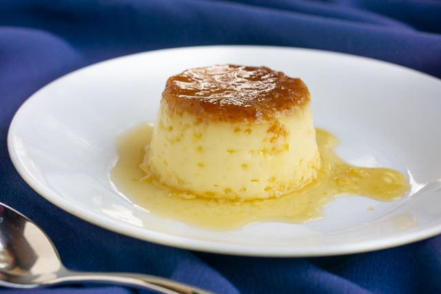 Individual serving of Spanish flan on a plate surrounded by caramel.  | www.CuriousCuisiniere.com 