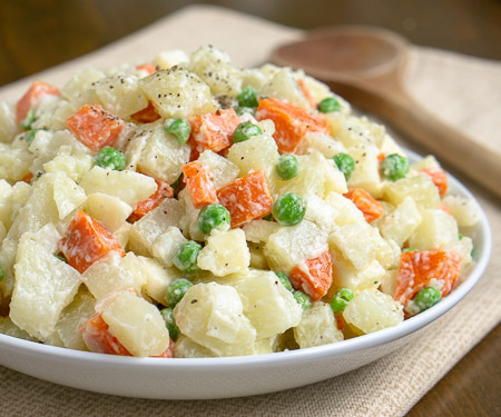Ensalada Rusa is the Spanish name for a side dish that is popular in many countries but is best known as Oliver Salad, or Russian Potato Salad. This well known potato salad is full of vegetables, like peas, carrots, onions, and more. | www.CuriousCuisiniere.com